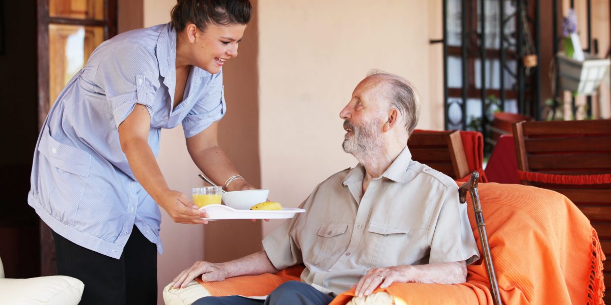 elderly senior being brought meal by carer or nurse